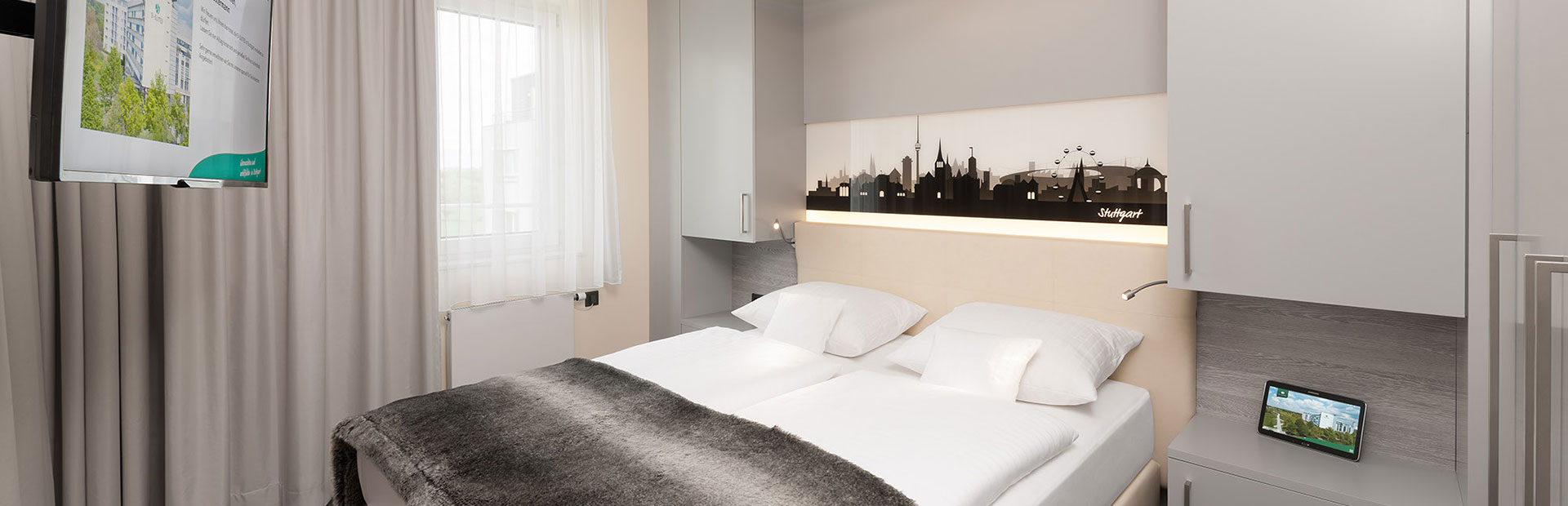 Schlafzimmer im Superior-Zimmer mit Stuttgarter Silhouette im SI-SUITES Hotel Stuttgart